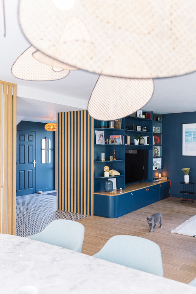Réalisation d'une salle de séjour design en bois de taille moyenne et fermée avec une bibliothèque ou un coin lecture, un mur bleu, parquet clair, un téléviseur encastré et un sol beige.