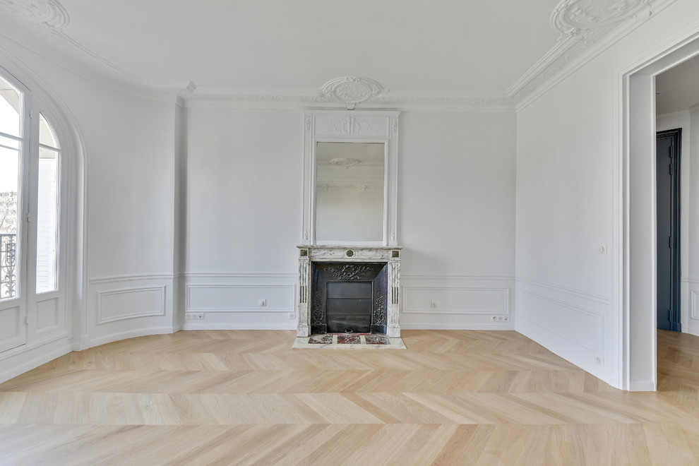 Mittelgroßes, Offenes Klassisches Wohnzimmer mit weißer Wandfarbe, hellem Holzboden, Kamin, Kaminumrandung aus Stein und braunem Boden in Paris