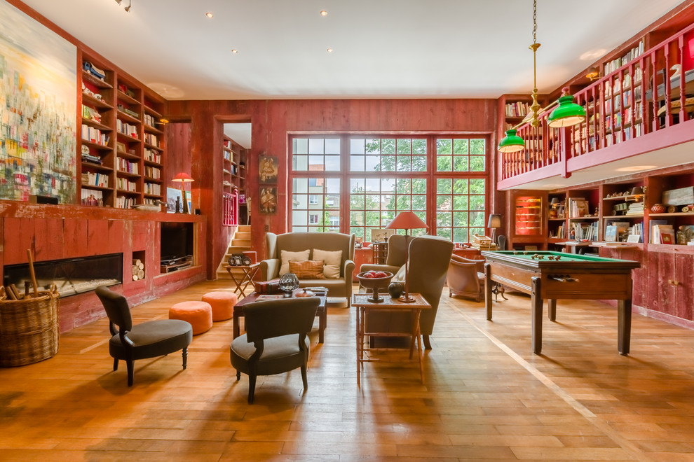 Abgetrennter Klassischer Hobbyraum mit roter Wandfarbe, hellem Holzboden, Gaskamin, Kaminumrandung aus Holz und beigem Boden