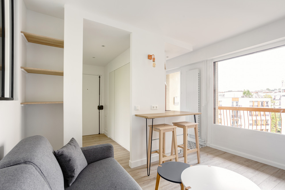 Modelo de sala de estar con barra de bar abierta nórdica pequeña sin chimenea con paredes blancas, suelo de madera clara, televisor independiente y suelo beige