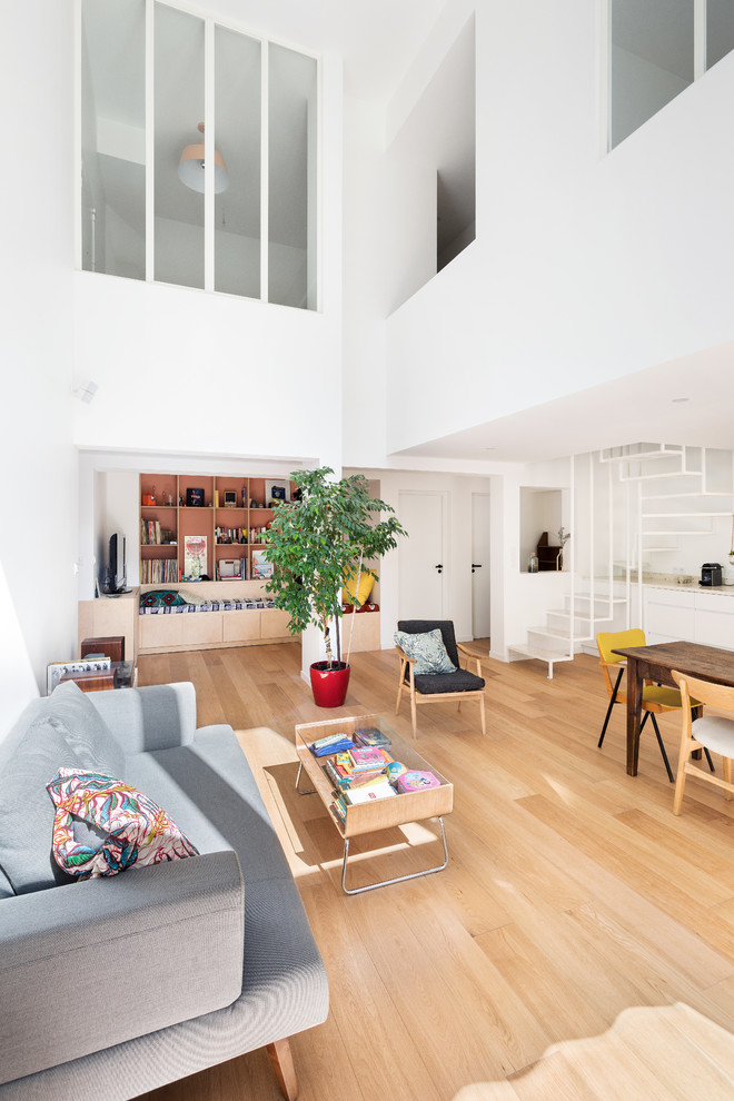 Foto di un soggiorno minimalista aperto con libreria e parquet chiaro