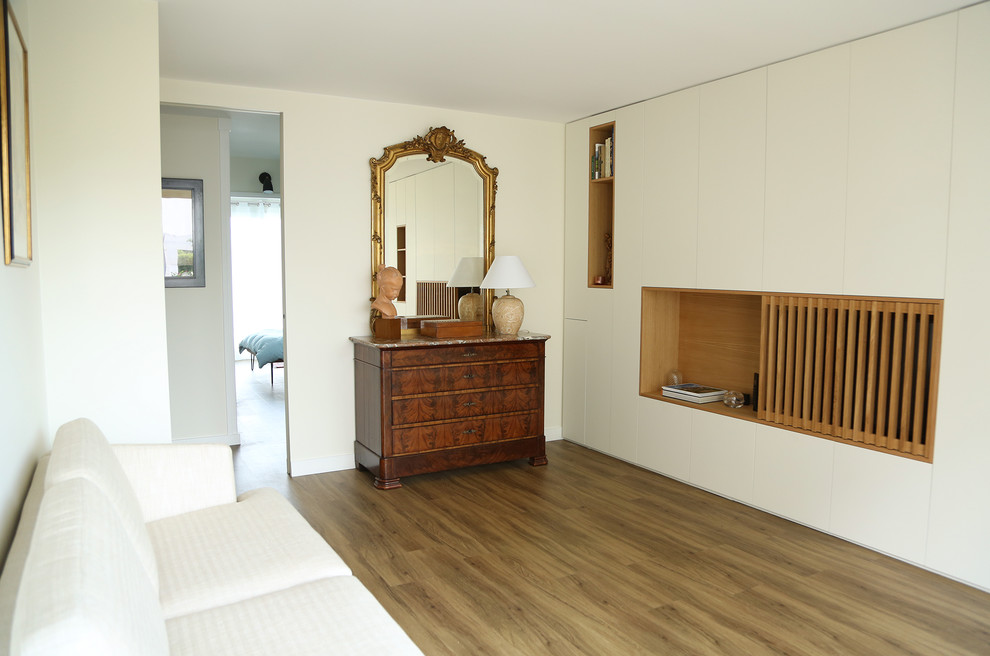 Exemple d'une salle de séjour tendance de taille moyenne et ouverte avec un mur beige, un sol en bois brun et un téléviseur dissimulé.