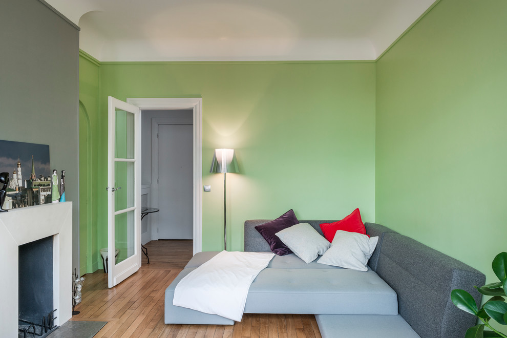 Exemple d'une salle de séjour tendance de taille moyenne avec un mur vert, parquet clair, une cheminée standard et un manteau de cheminée en pierre.