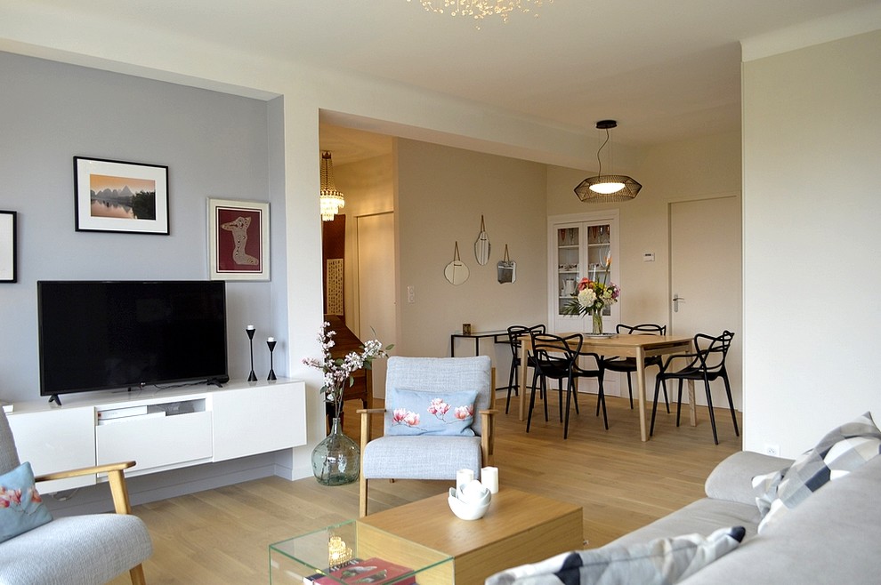 Ispirazione per un soggiorno design di medie dimensioni e aperto con pareti bianche, parquet chiaro, TV autoportante e pavimento beige