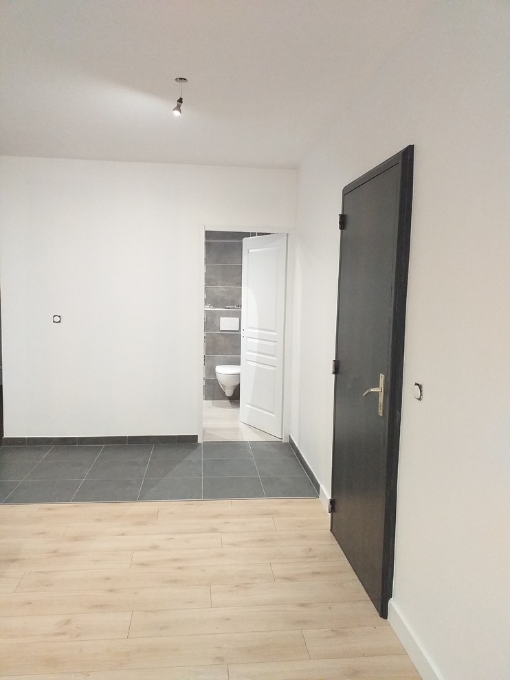 Large modern open plan games room in Lyon with white walls, ceramic flooring, no fireplace and grey floors.