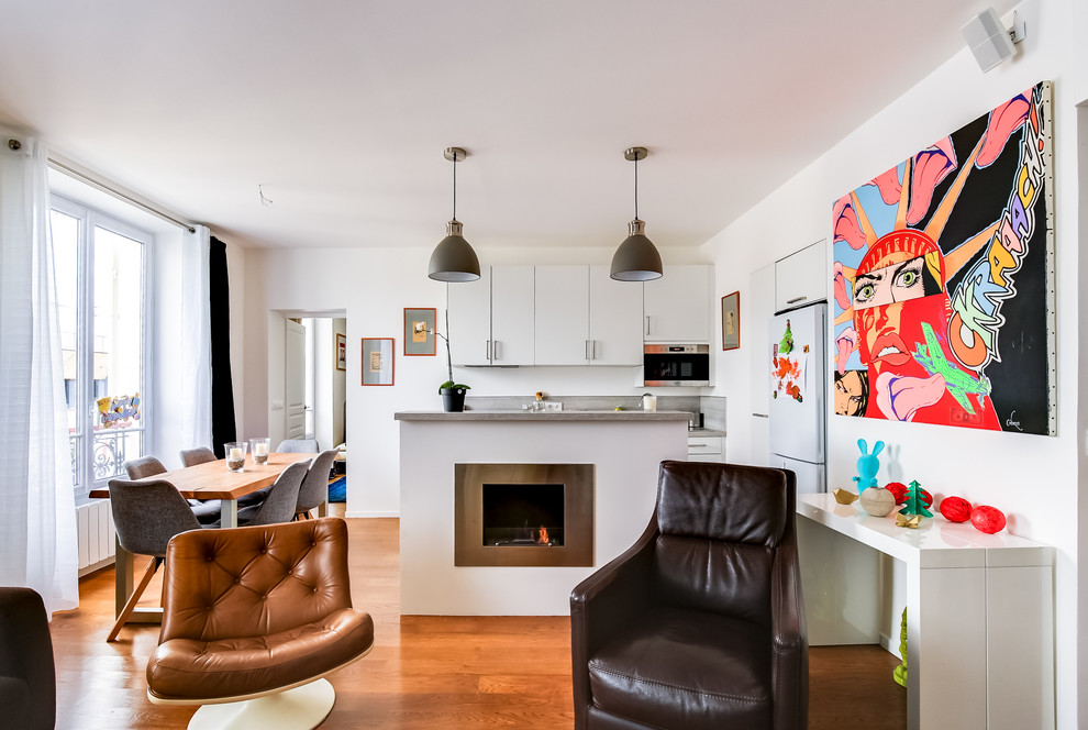 Mittelgroßes, Offenes Modernes Wohnzimmer mit Hausbar, weißer Wandfarbe, hellem Holzboden, Kamin, Kaminumrandung aus Metall, TV-Wand und braunem Boden in Paris