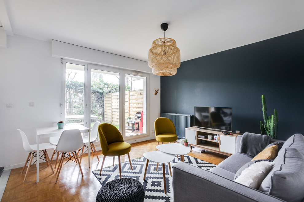 Immagine di un soggiorno scandinavo di medie dimensioni e aperto con pareti blu, parquet chiaro e TV autoportante