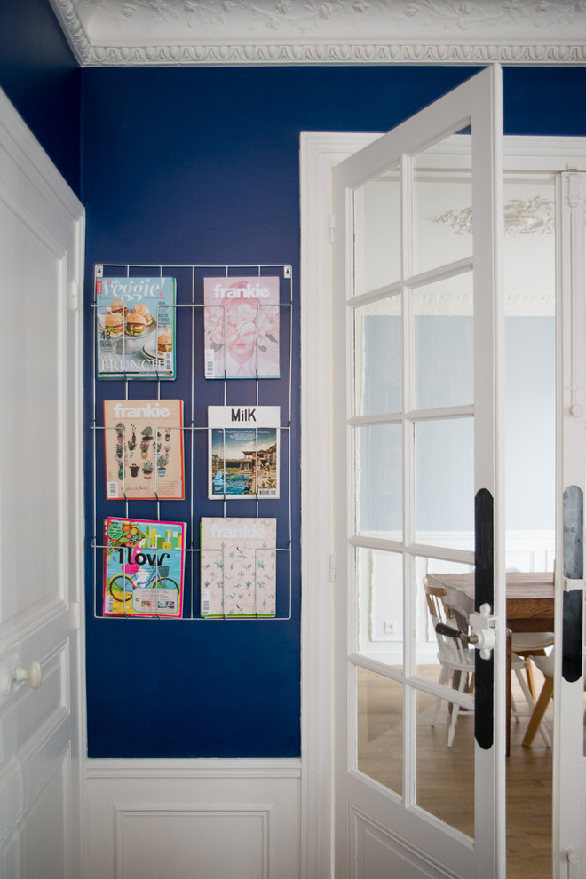 パリにある高級な広い北欧スタイルのおしゃれなオープンリビング (ライブラリー、青い壁、淡色無垢フローリング、コーナー設置型暖炉、石材の暖炉まわり、テレビなし) の写真