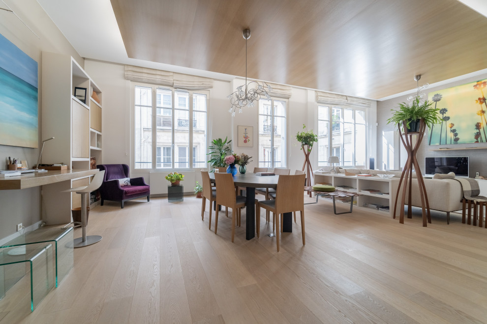 Imagen de sala de estar abierta moderna grande sin chimenea con paredes beige, suelo de madera clara, televisor independiente, suelo beige y madera