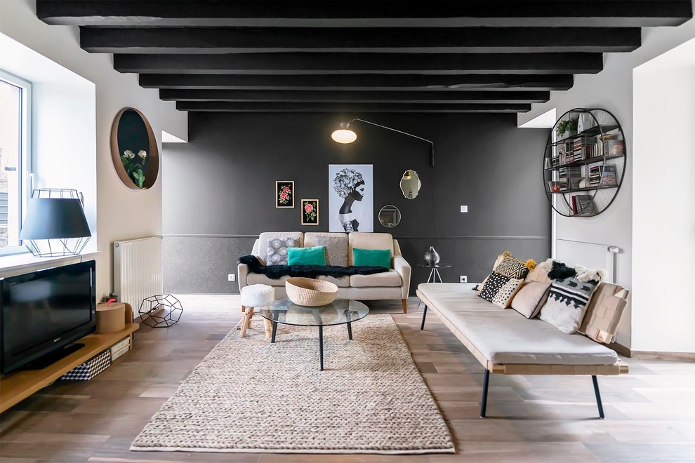 Großes, Offenes Stilmix Wohnzimmer ohne Kamin mit schwarzer Wandfarbe, hellem Holzboden und freistehendem TV in Sonstige
