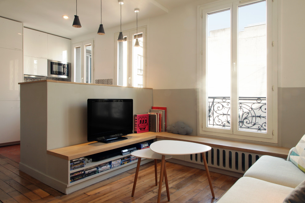 На фото: маленькая открытая гостиная комната в скандинавском стиле с светлым паркетным полом, телевизором на стене и разноцветными стенами без камина для на участке и в саду с