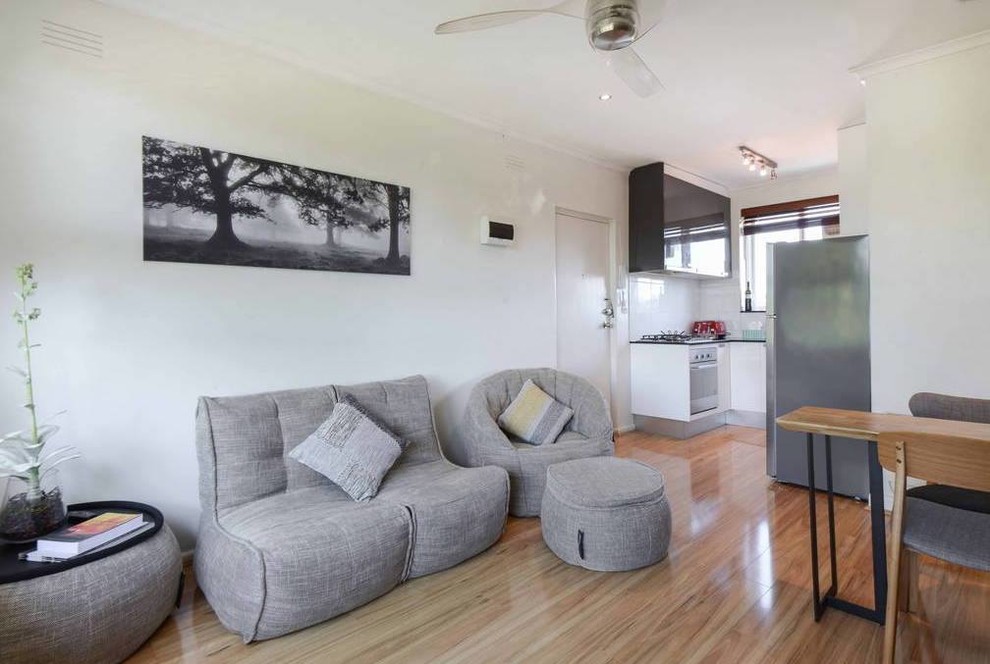 Modelo de sala de estar abierta actual pequeña con paredes blancas, suelo de madera clara y suelo marrón
