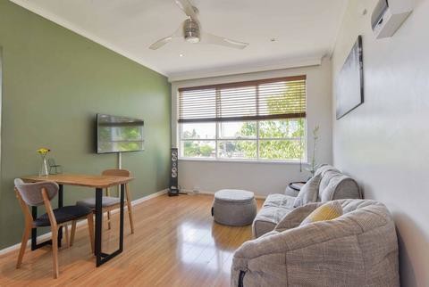 This is an example of a small contemporary open plan games room in Other with green walls, light hardwood flooring, a wall mounted tv and brown floors.