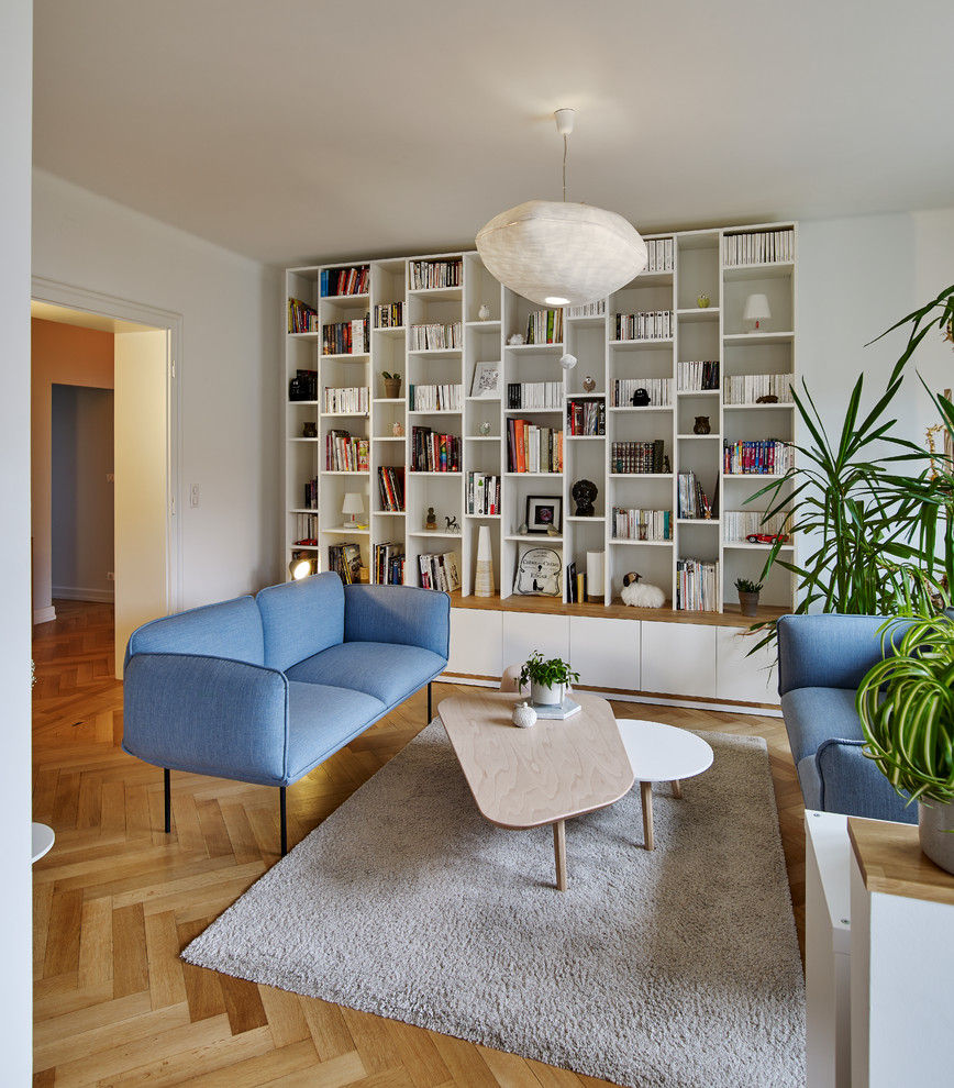 Esempio di un grande soggiorno nordico aperto con libreria, pareti bianche, parquet chiaro e pavimento beige