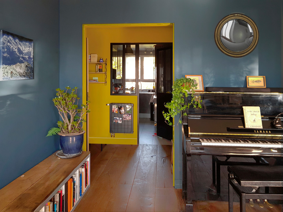 Idées déco pour une salle de séjour rétro de taille moyenne avec une salle de musique, un mur bleu, parquet clair et un sol marron.