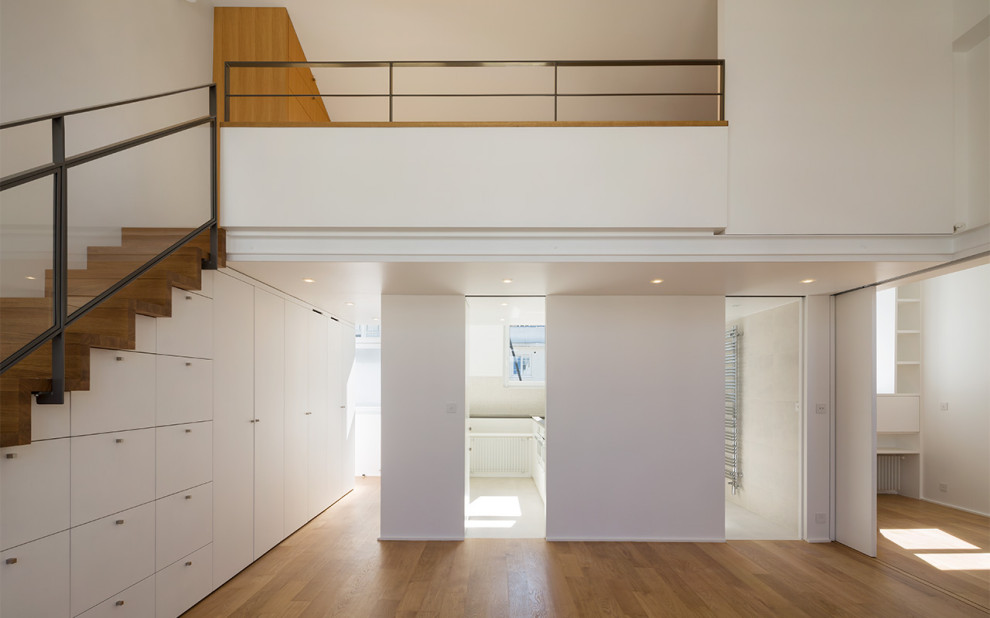 Cette image montre une salle de séjour design ouverte avec un mur blanc et parquet clair.