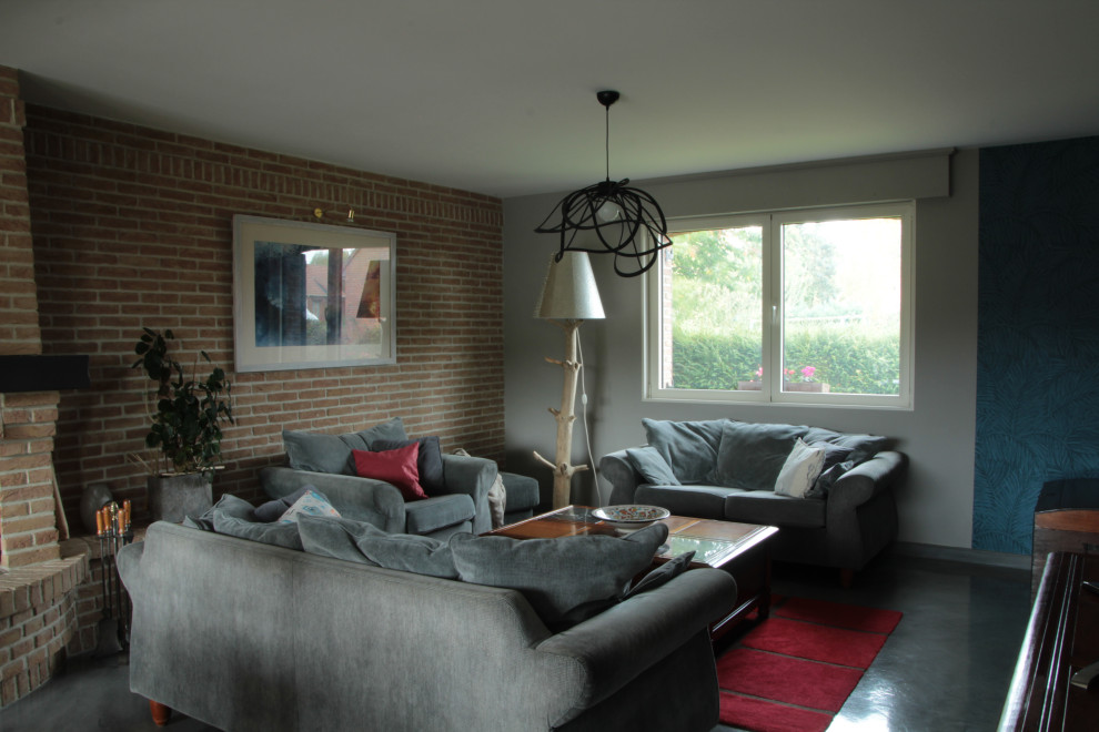 リールにある中くらいなコンテンポラリースタイルのおしゃれなオープンリビング (グレーの壁、コンクリートの床、薪ストーブ、レンガの暖炉まわり、グレーの床) の写真