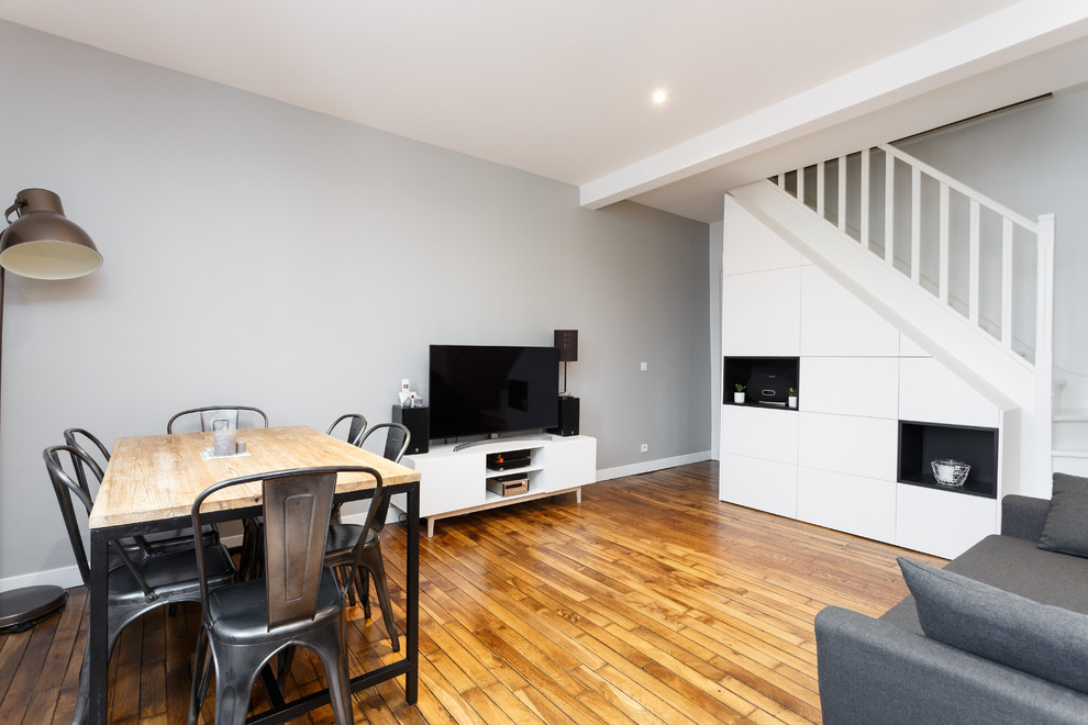 Kleines, Offenes Modernes Wohnzimmer ohne Kamin mit weißer Wandfarbe, braunem Holzboden, freistehendem TV und braunem Boden in Paris