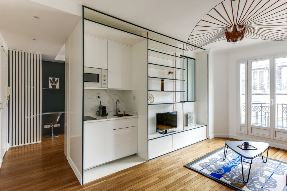 Modelo de sala de estar abierta contemporánea pequeña con paredes azules, suelo de madera en tonos medios, chimenea de esquina y suelo beige