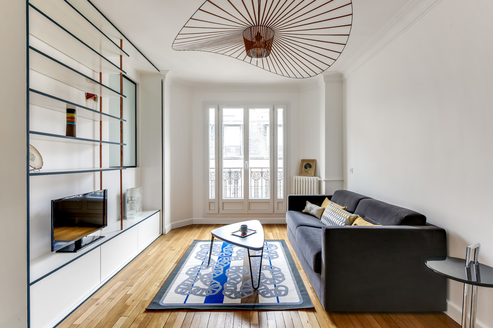 Abgetrenntes, Mittelgroßes Nordisches Wohnzimmer mit braunem Holzboden, beigem Boden, weißer Wandfarbe und freistehendem TV in Paris