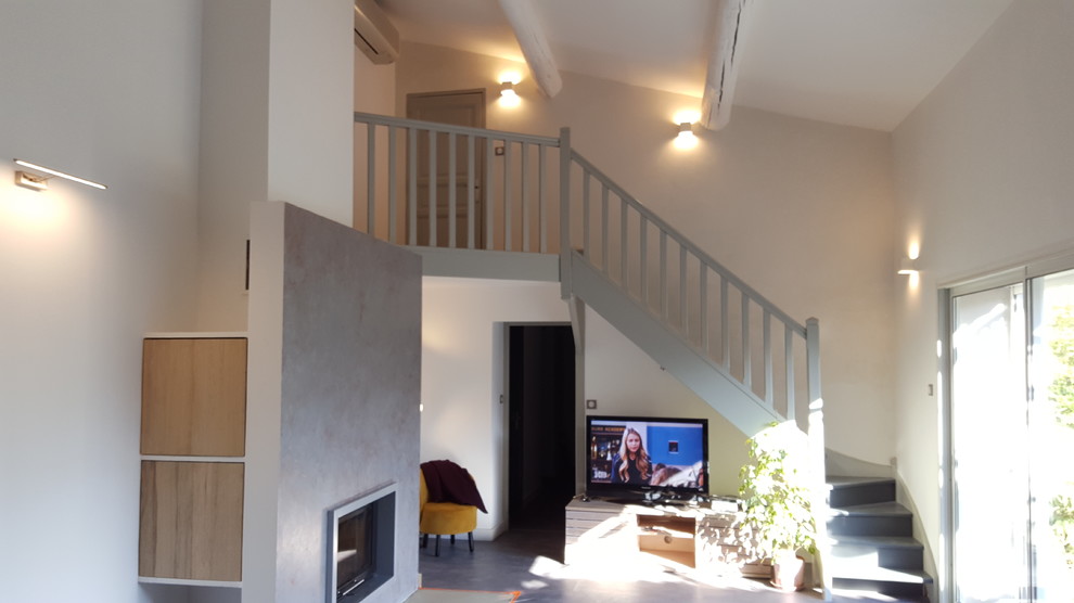 Пример оригинального дизайна: открытая гостиная комната среднего размера в современном стиле с белыми стенами, пробковым полом, стандартным камином, фасадом камина из штукатурки, отдельно стоящим телевизором и серым полом