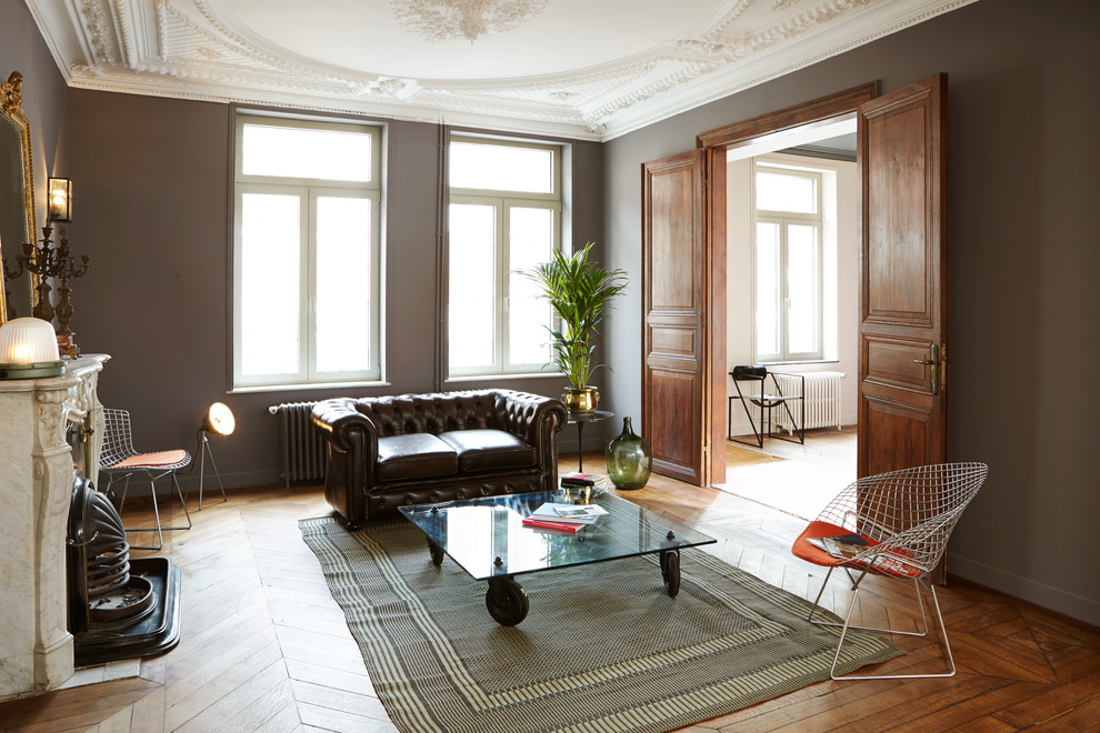 Großes, Fernseherloses, Abgetrenntes Stilmix Wohnzimmer mit grauer Wandfarbe, braunem Holzboden, Kamin und Kaminumrandung aus Stein in Lille