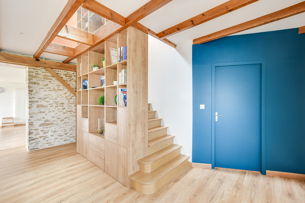 Cette image montre une salle de séjour rustique ouverte avec une bibliothèque ou un coin lecture, un mur bleu, parquet clair et aucun téléviseur.