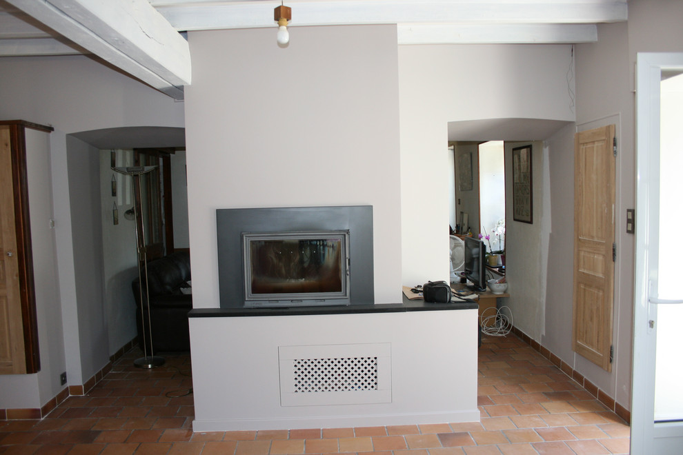 Exemple d'une salle de séjour nature de taille moyenne et ouverte avec une cheminée standard, un mur beige, tomettes au sol, un manteau de cheminée en plâtre, un téléviseur fixé au mur et un sol rouge.