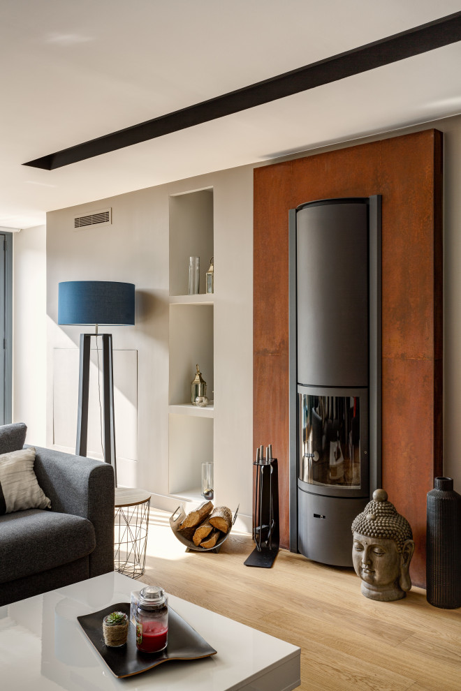 Idée de décoration pour une grande salle de séjour design ouverte avec un mur beige, parquet clair, un poêle à bois, un manteau de cheminée en métal, un téléviseur indépendant et un sol marron.