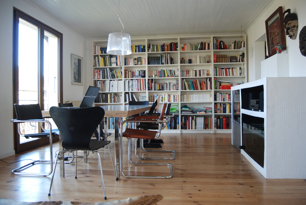 This is an example of a contemporary games room in Lyon with a reading nook, white walls, medium hardwood flooring, a built-in media unit and beige floors.