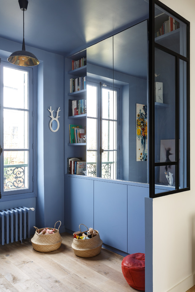 Свежая идея для дизайна: открытая гостиная комната среднего размера в современном стиле с с книжными шкафами и полками, синими стенами, светлым паркетным полом, скрытым телевизором и бежевым полом без камина - отличное фото интерьера