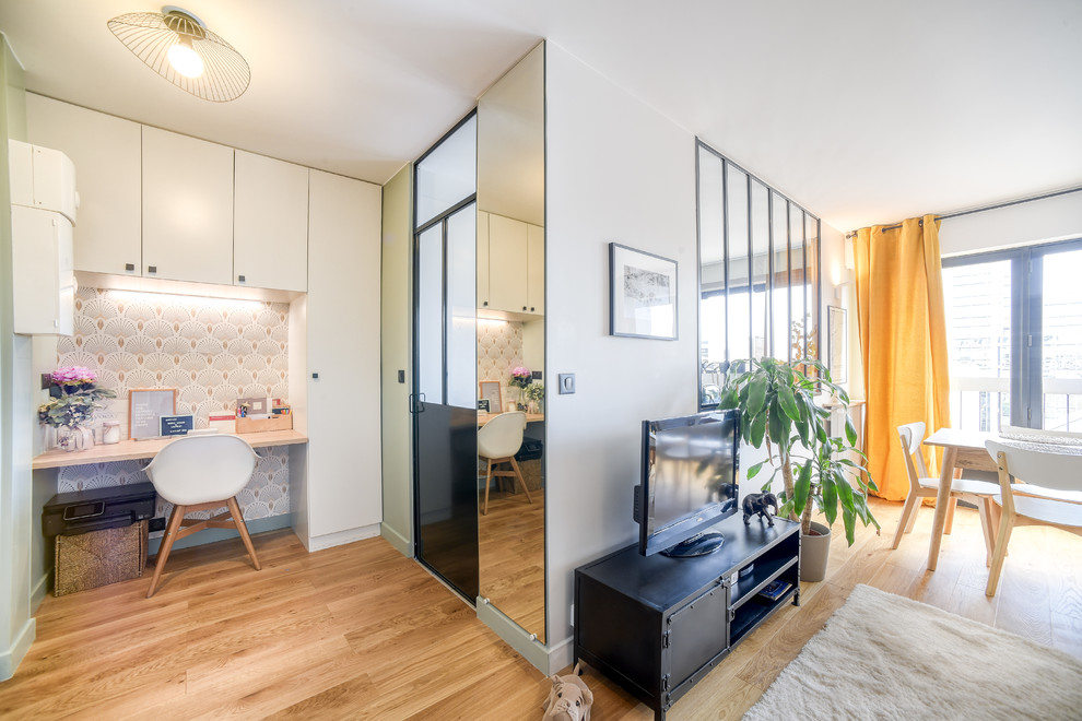 Cette image montre une salle de séjour design ouverte et de taille moyenne avec un mur vert, parquet clair, aucune cheminée, un téléviseur indépendant et un sol marron.