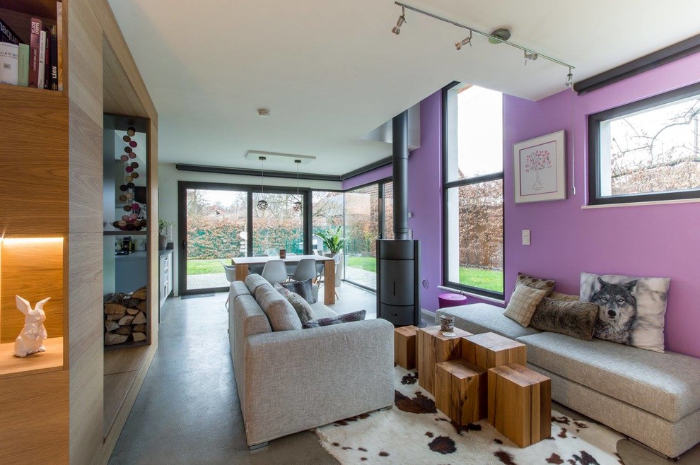 Immagine di un grande soggiorno aperto con pareti bianche, pavimento in cemento, stufa a legna, TV nascosta e pavimento grigio