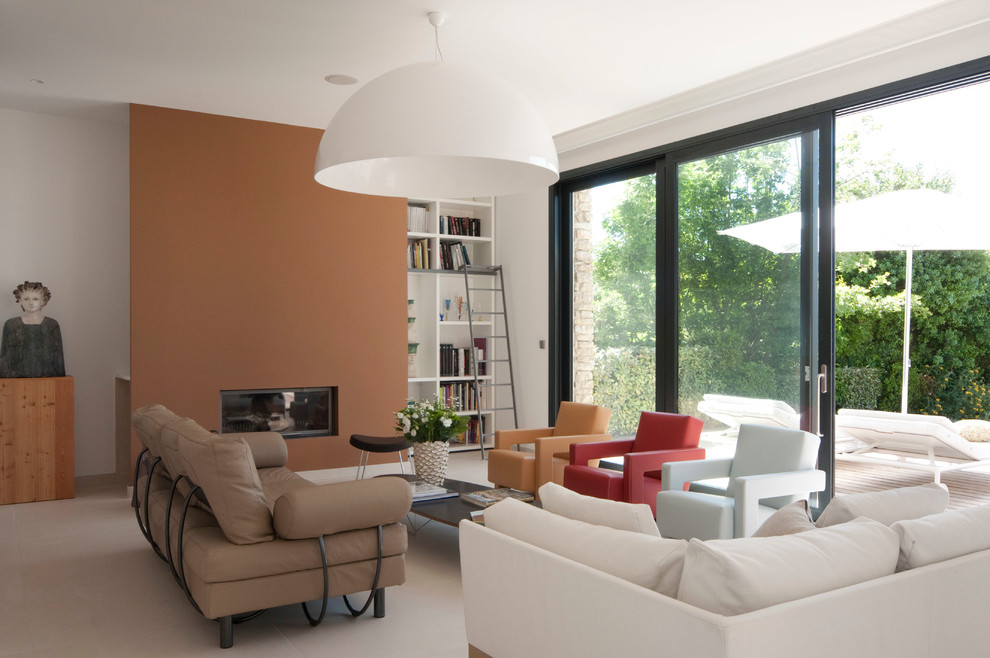 На фото: открытая гостиная комната среднего размера в современном стиле с с книжными шкафами и полками и оранжевыми стенами без телевизора с