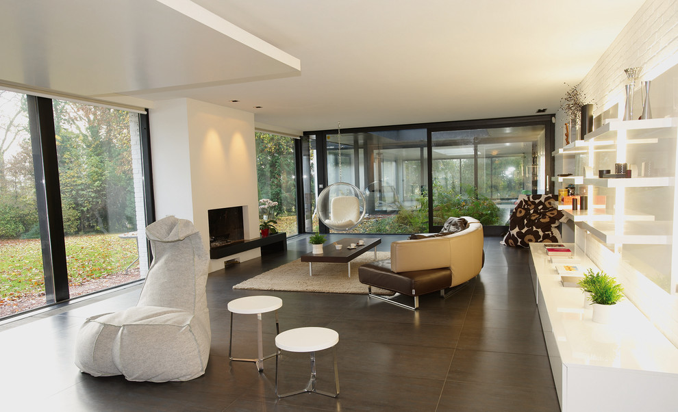 Идея дизайна: большая открытая гостиная комната в стиле модернизм с бежевыми стенами, полом из керамической плитки, стандартным камином, фасадом камина из штукатурки, отдельно стоящим телевизором и серым полом