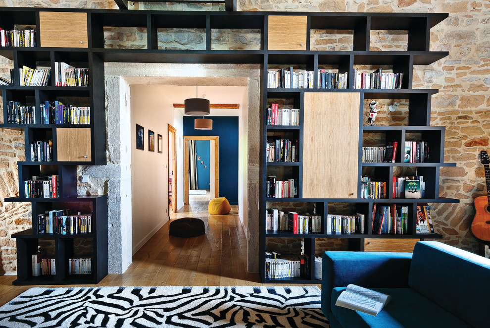 Imagen de sala de estar con biblioteca abierta contemporánea de tamaño medio sin chimenea y televisor con paredes beige, suelo de madera en tonos medios y alfombra