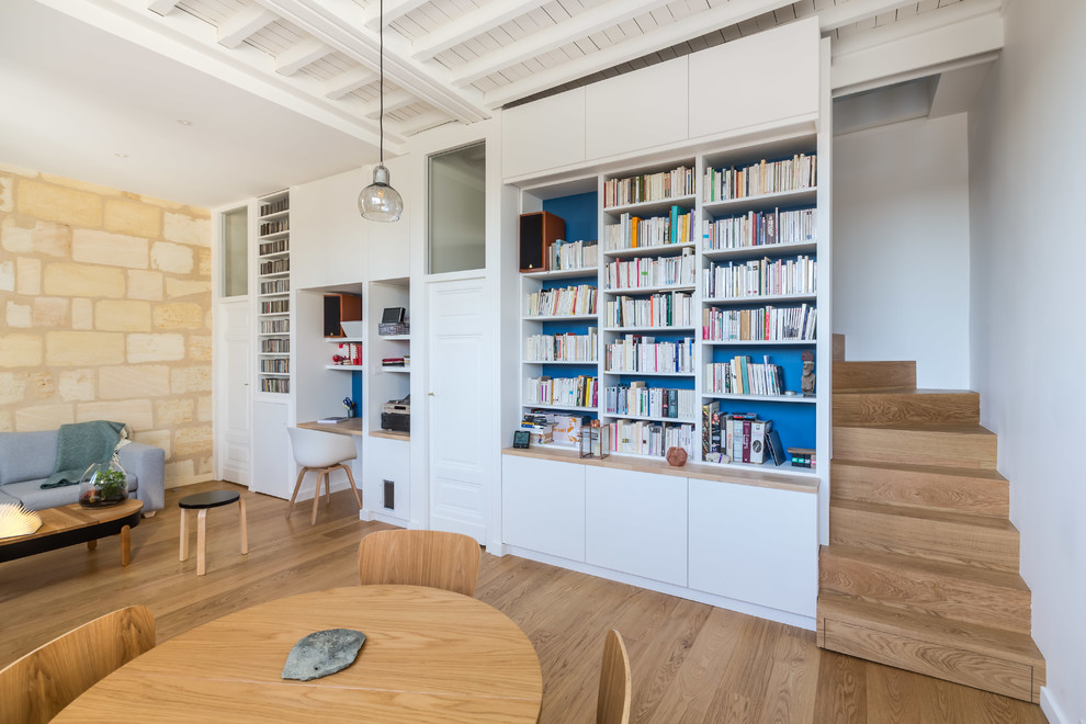 Foto di un soggiorno minimal con libreria, pareti blu e parquet chiaro