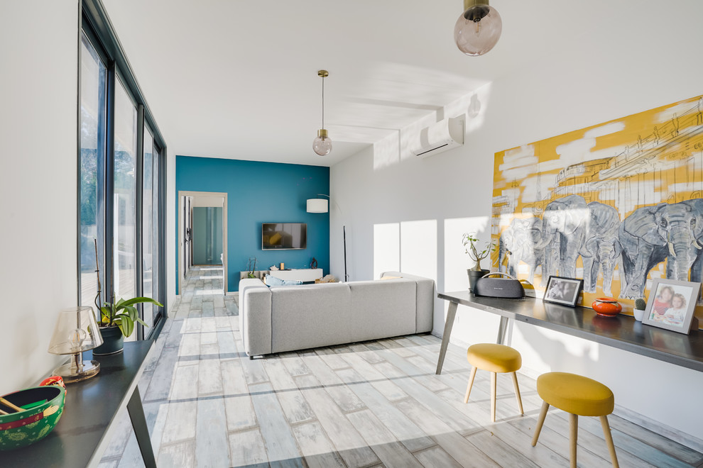 Réalisation d'une grande salle de séjour design ouverte avec un mur bleu, parquet peint, aucune cheminée, un téléviseur fixé au mur et un sol gris.