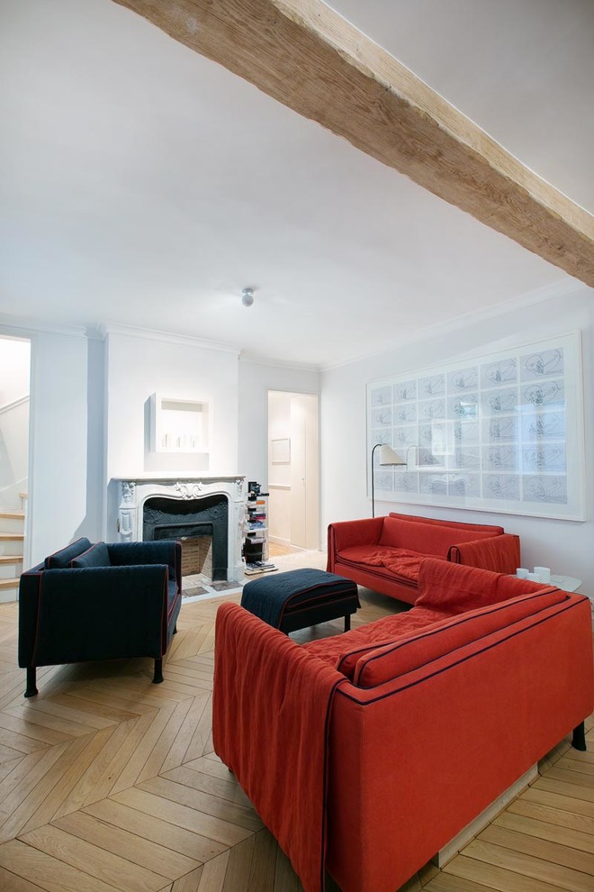Mittelgroßes, Fernseherloses, Offenes Modernes Wohnzimmer mit weißer Wandfarbe, braunem Holzboden, Kamin und Kaminumrandung aus Stein in Paris