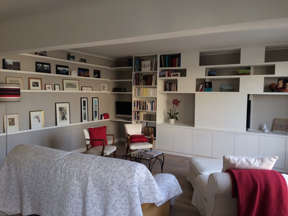 Réalisation d'une grande salle de séjour design ouverte avec une bibliothèque ou un coin lecture, un mur blanc, parquet clair et un téléviseur dissimulé.