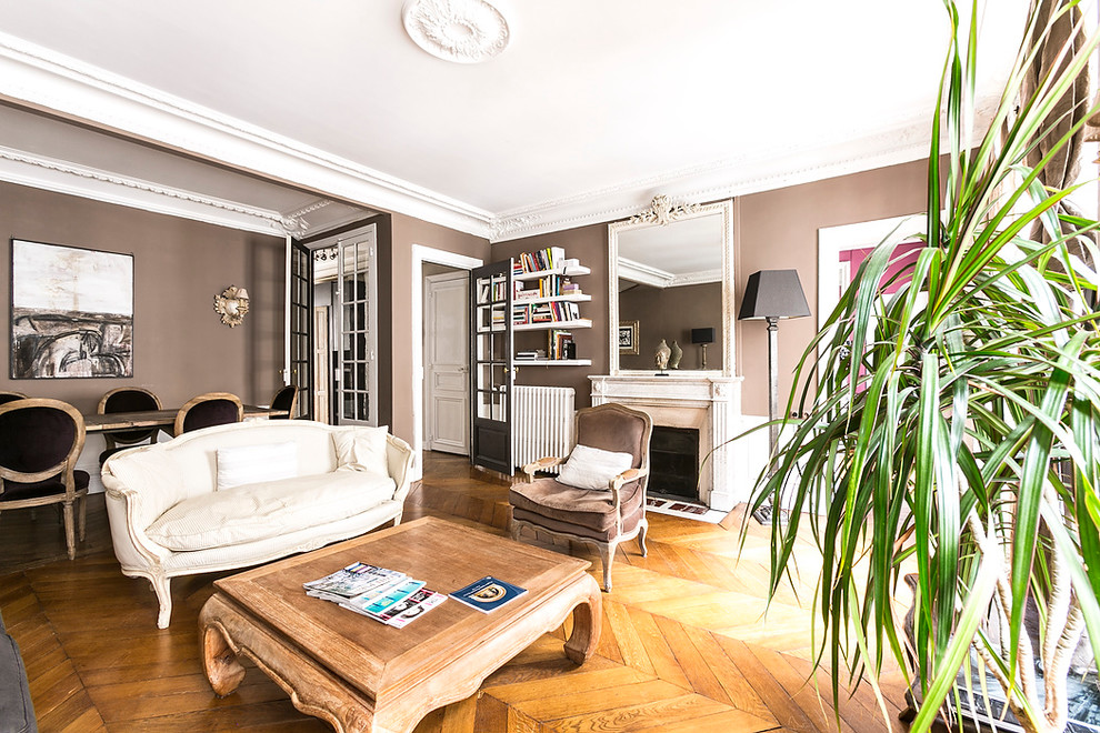 Große, Fernseherlose, Offene Klassische Bibliothek mit beiger Wandfarbe, braunem Holzboden, Kamin und Kaminumrandung aus Stein in Paris