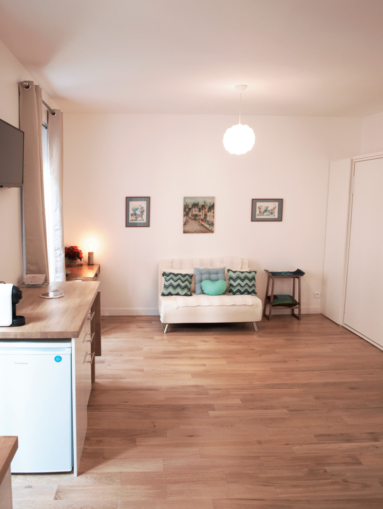 Cette image montre une petite salle de séjour nordique ouverte avec un mur blanc, parquet clair, aucune cheminée, un téléviseur fixé au mur et un sol beige.
