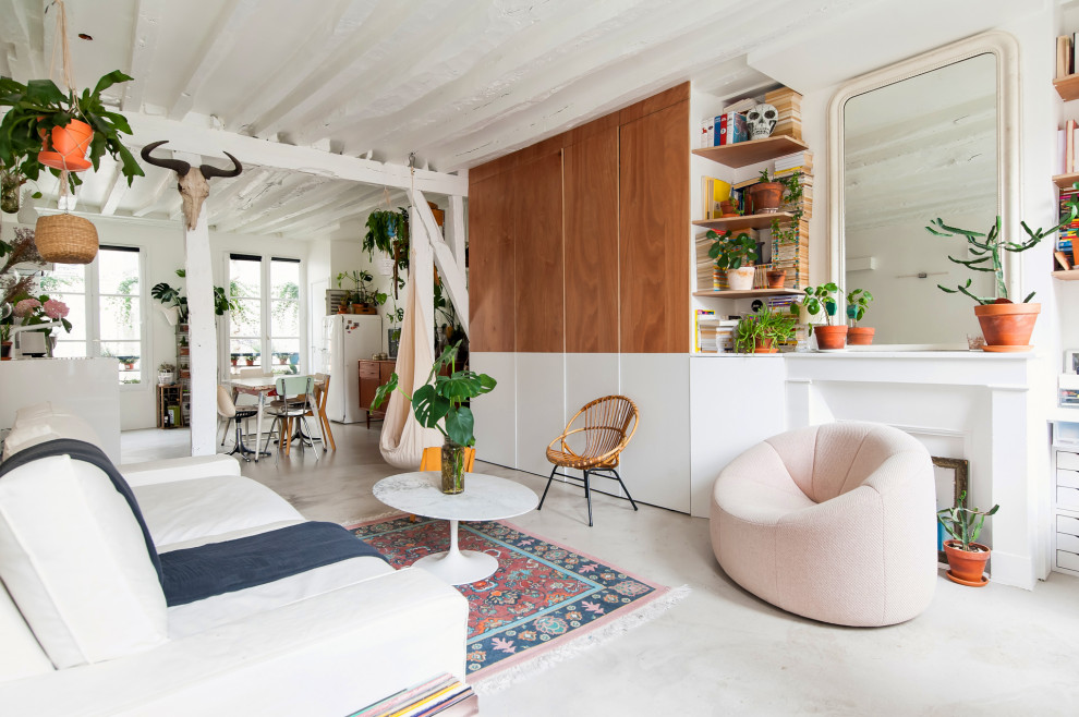 Photo of a medium sized bohemian games room in Paris with a reading nook, white walls, concrete flooring, a standard fireplace, a plastered fireplace surround, no tv and grey floors.