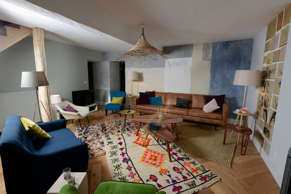 Diseño de sala de estar abierta actual grande sin chimenea con suelo de madera en tonos medios, televisor independiente y paredes multicolor