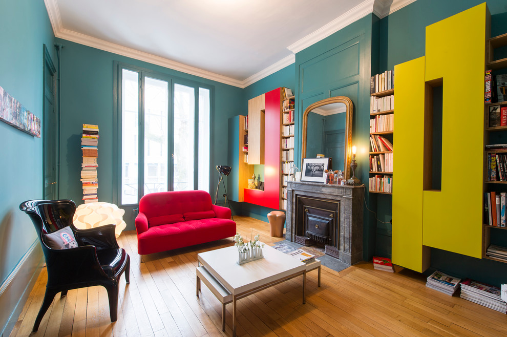 Modelo de sala de estar con biblioteca cerrada contemporánea de tamaño medio con paredes azules, suelo de madera en tonos medios, todas las chimeneas y marco de chimenea de piedra