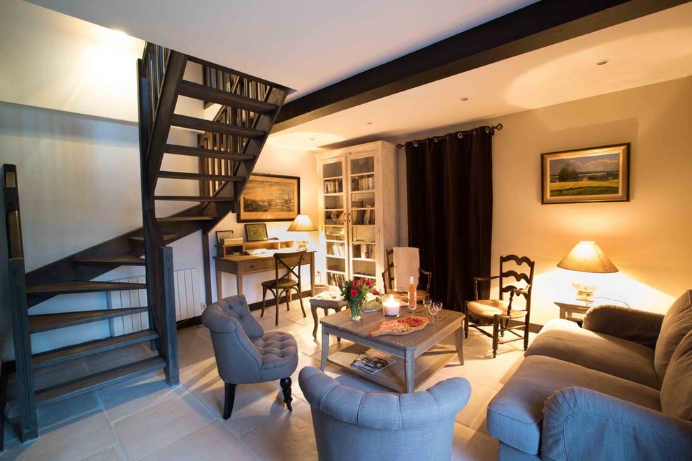 Modelo de sala de estar con biblioteca abierta de estilo de casa de campo de tamaño medio con paredes beige, suelo de baldosas de terracota y suelo beige