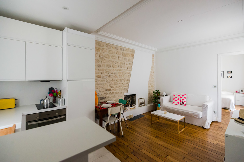 Kleines, Offenes Skandinavisches Wohnzimmer mit braunem Holzboden, Kaminofen, weißer Wandfarbe und Kaminumrandung aus Backstein in Paris