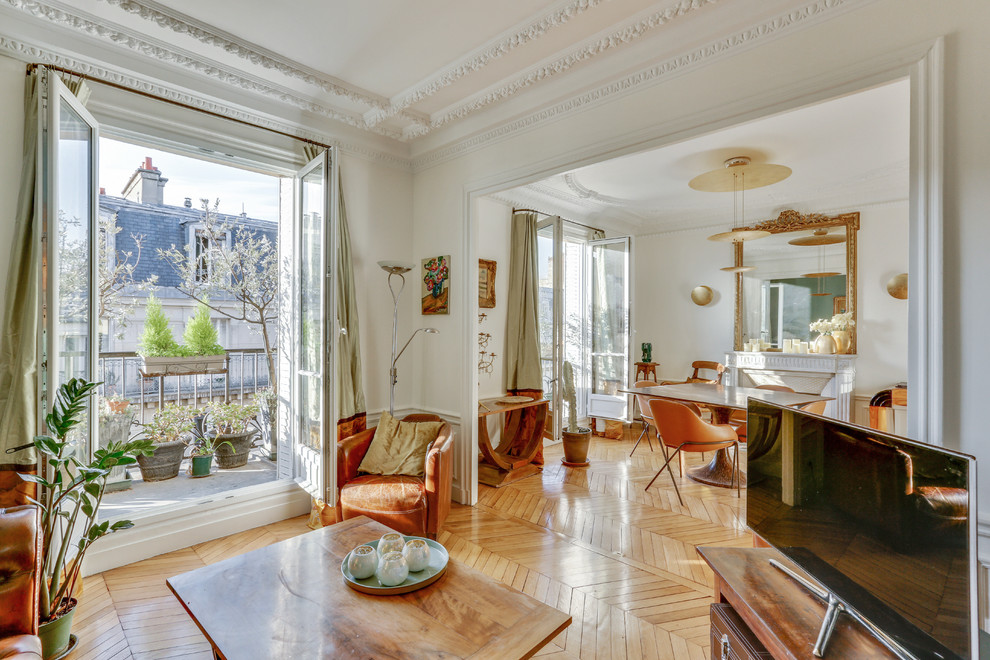 Foto di un soggiorno classico aperto con pareti bianche, pavimento in legno massello medio, TV autoportante, pavimento marrone e camino classico