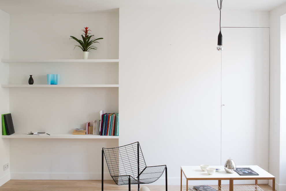 Exempel på ett minimalistiskt allrum, med vita väggar och ljust trägolv