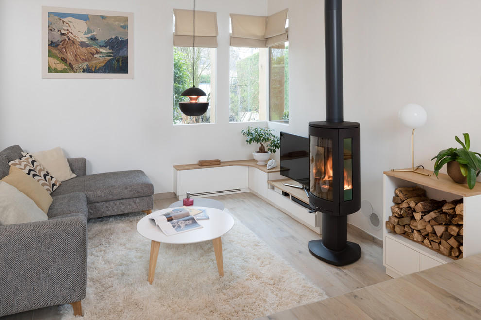 Idées déco pour une salle de séjour scandinave ouverte avec un mur blanc, parquet clair, un poêle à bois, un manteau de cheminée en métal, un téléviseur indépendant et un sol beige.